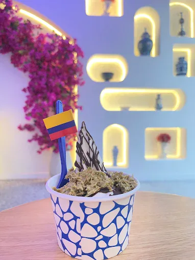 Vaso de helado de yogurt griego con pistacho y una banderita de Colombia, servido en el local